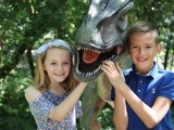 Smiling kids with a dinosaur, at our theme parks for 5 year olds. 